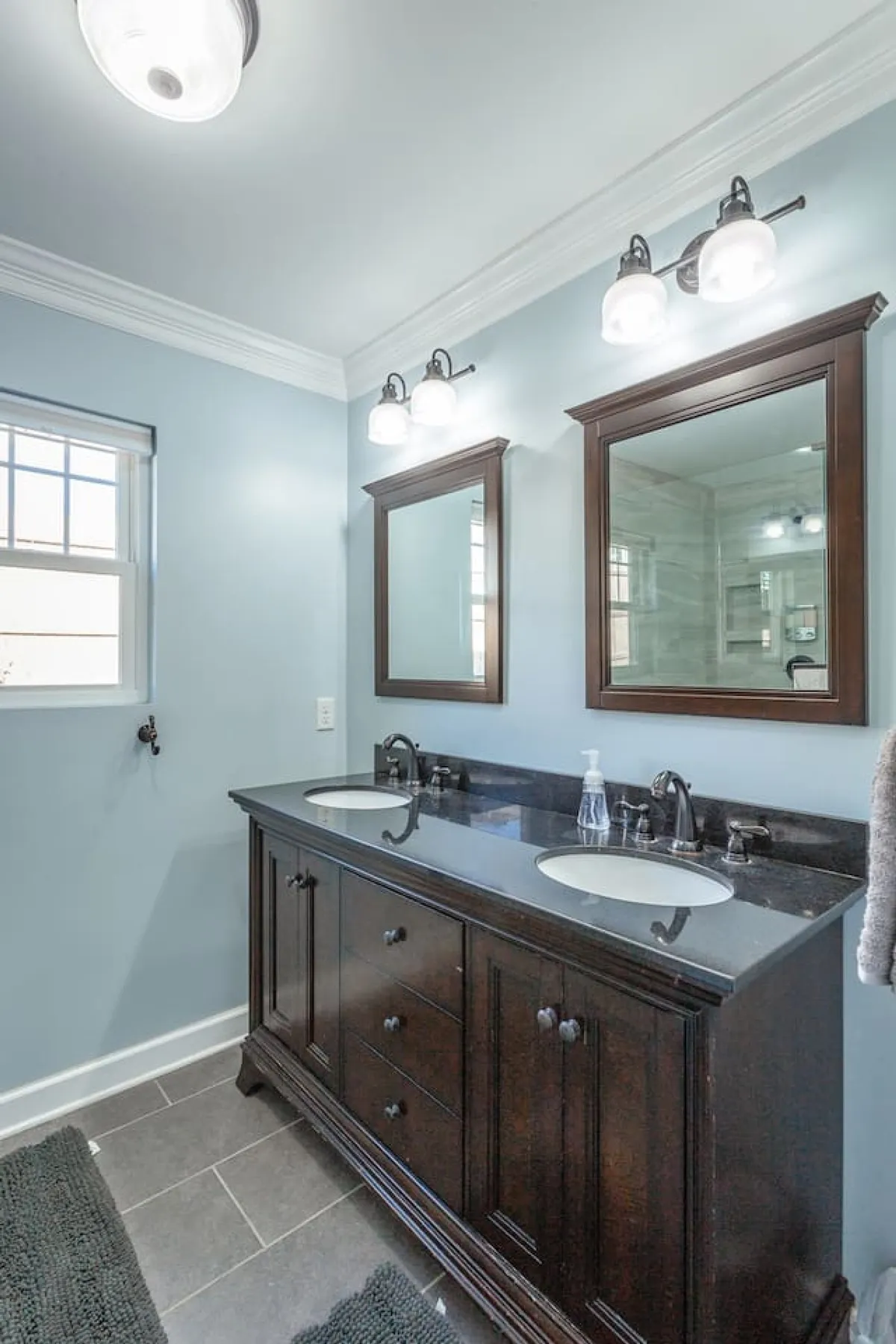 A spacious bathroom is featured, with a double sink vanity, sleek mirrors, and modern light fixtures. The calming color palette and organized counters create a refreshing atmosphere perfect for group routines.