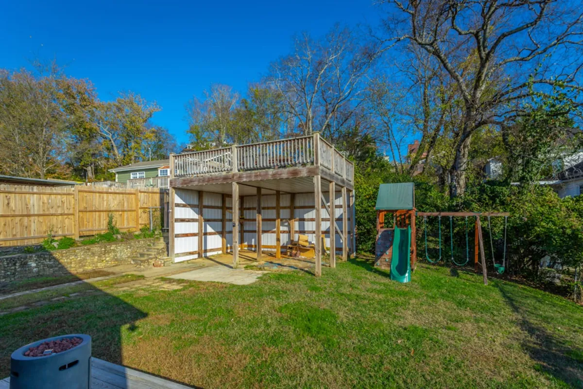 A cheerful backyard scene featuring a deck, swingset, and open grass area. The space is well-suited for outdoor relaxation, family gatherings, and playful activities, making it ideal for groups looking to socialize after returning from city adventures.