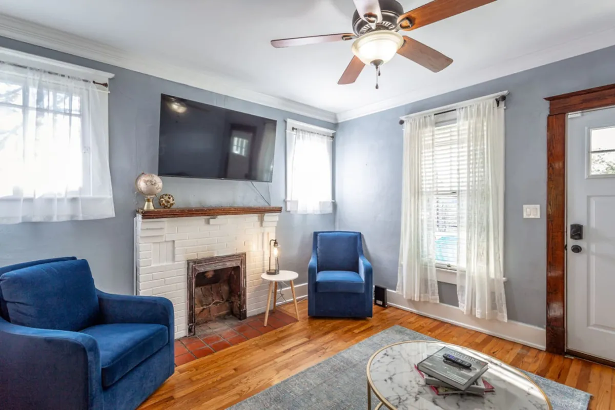A comfortable living area with blue armchairs, a fireplace, a TV, and a coffee table. The space is designed for relaxing, watching movies, or engaging in cozy conversations.