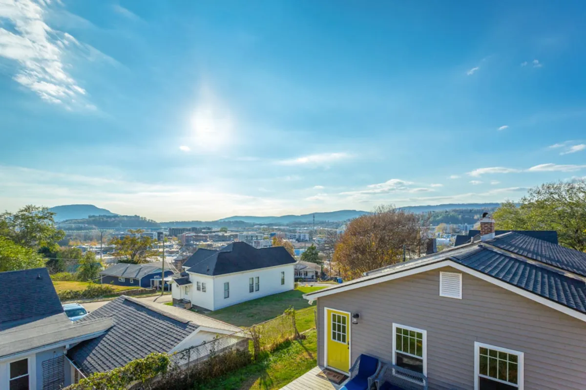 A wide view of distant mountains and a blue sky, with houses in the foreground. The tranquil setting hints at the scenic beauty surrounding the property and gives a sense of the adventure and exploration available nearby.